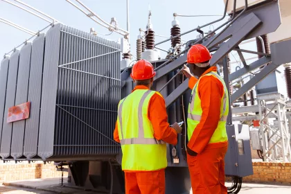 electricians standing next to a transformer in electrical power plant