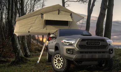 Toyota Tacoma with a tent at a forest camp