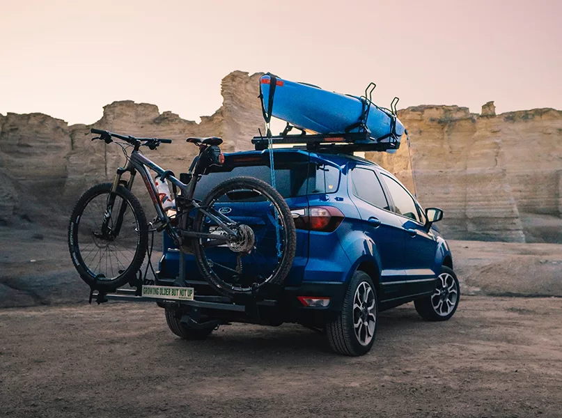 blue suv with bike and kayak off-road